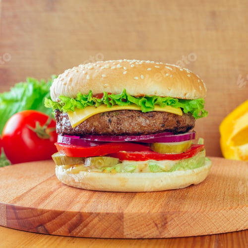 Preview: Juicy hamburger layered with fresh vegetables served on a wooden cutting board at a casual setting