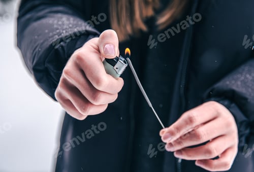 Preview: Close-up of a woman setting fire to a sparkler with a lighter.