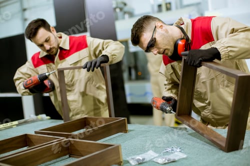 Preview: Two young workers assembling furniture in the factory