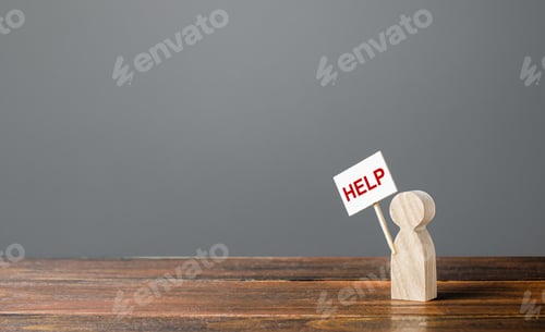 Wooden Figure Holding Sign Demanding Help on Table