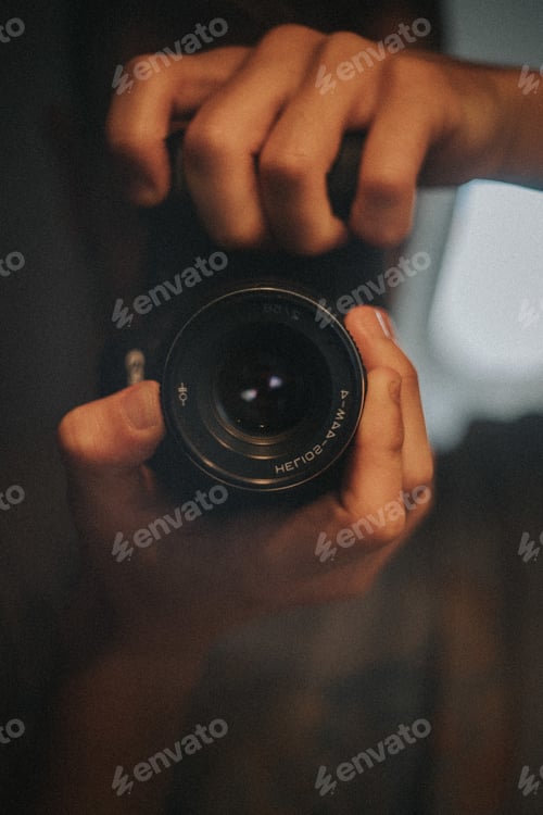 Preview: Vertical shot of a photographer holding the black camera with two hands