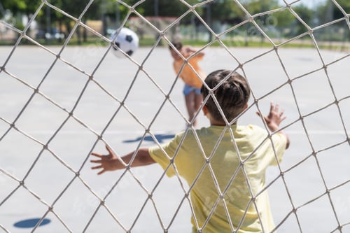 Preview: Kids playing soccer outdoors through a goal net