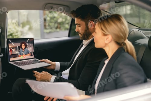Preview: Smiling business people have online meeting using laptop while sitting in car back seats