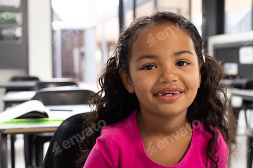 Preview: Biracial girl with curly hair smiles in a school classroom setting