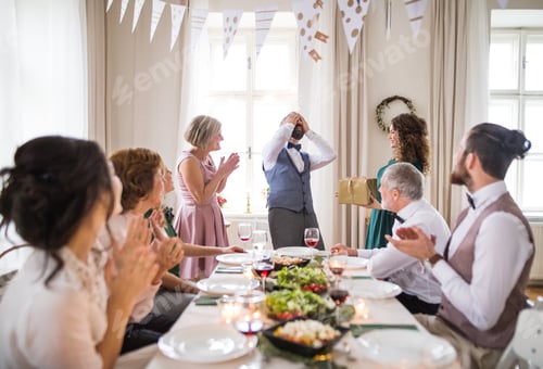 Preview: A woman giving gift to a mature man on a family birthday party.