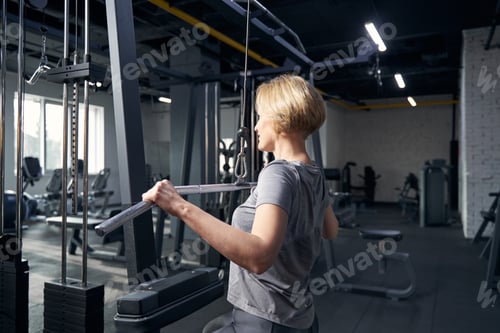 Preview: Woman using gym equipment during strength workout