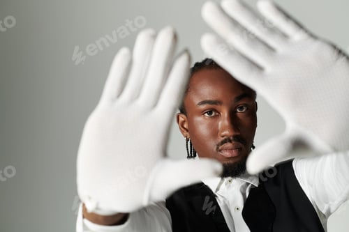 Preview: Young African American man in suit and vest poses confidently against a sleek grey backdrop