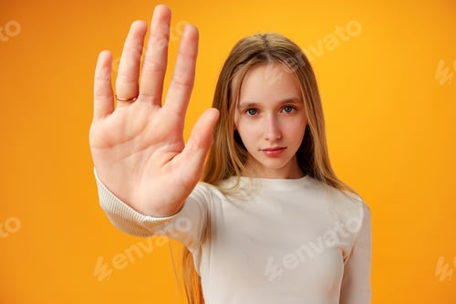 Preview: Teen girl extend hand in block gesture against yellow background