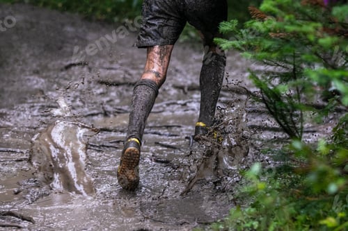 Preview: Legs athlete running puddles of mud in heavy rain