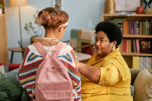 Preview: Senior Woman Helping Granddaughter with Backpack at Home