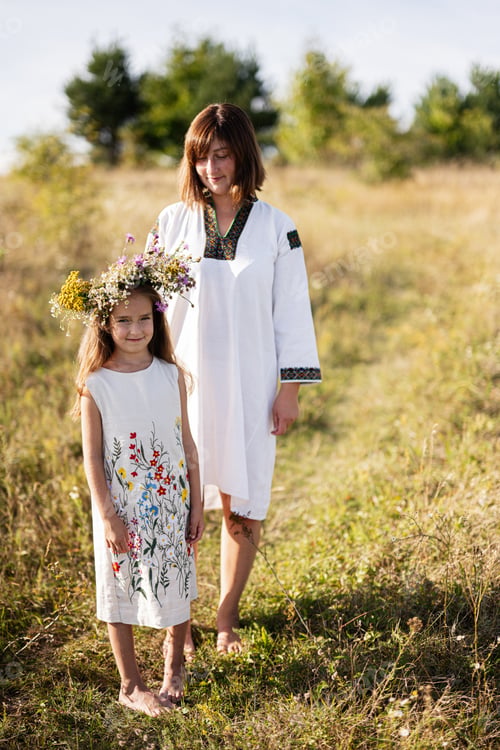 Preview: Mother and daughter in embroidered dresses in sunny field