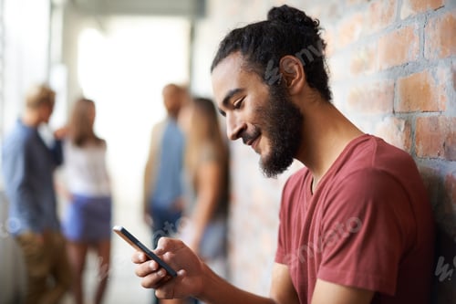 Preview: A young man using a mobile phone with his friends standing in the background