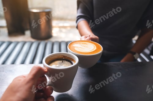 Preview: Closeup image of a man and a woman clinking white coffee mugs in cafe