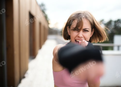 Preview: A young woman practising karate outdoors on terrace.