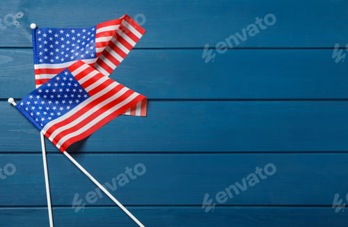 Preview: American flags on blue wooden table, flat lay with space for text. Memorial Day