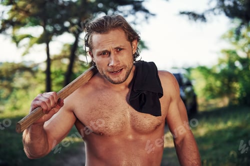 Preview: Handsome shirtless man with muscular body type is in the forest at daytime