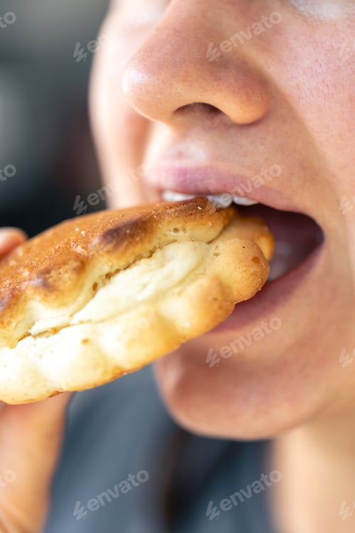 Preview: Detailed shot of a woman eating fresh bun.