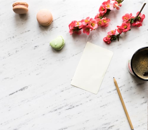 Preview: Top view of notebook, coffee, macarons and flowers on marble bac
