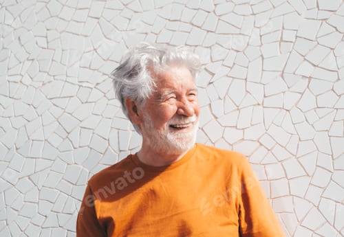 Preview: Handsome happy white haired senior man sitting outdoors under the sun looking at side