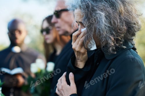 Preview: Senior woman with grey hair wiping tears with handkerchief at funeral