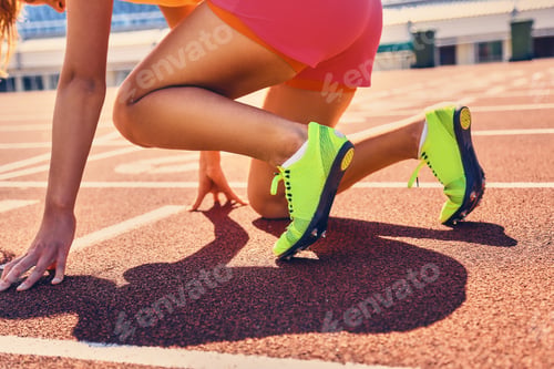 Preview: Blond sporty female runner to quick start position.