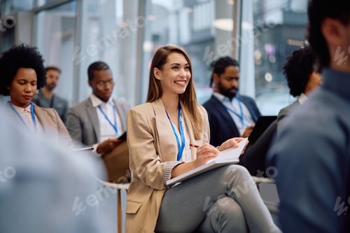 Preview: Young happy businesswoman attending a seminar in conference hall.