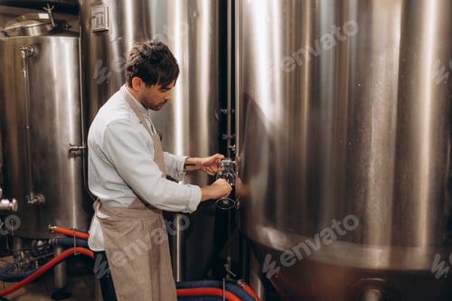 Preview: brewer at brewery pours beer into a glass from the tank for inspection