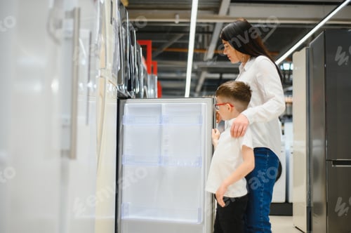 Preview: Happy mother with son choosing refrigerator in home appliance store