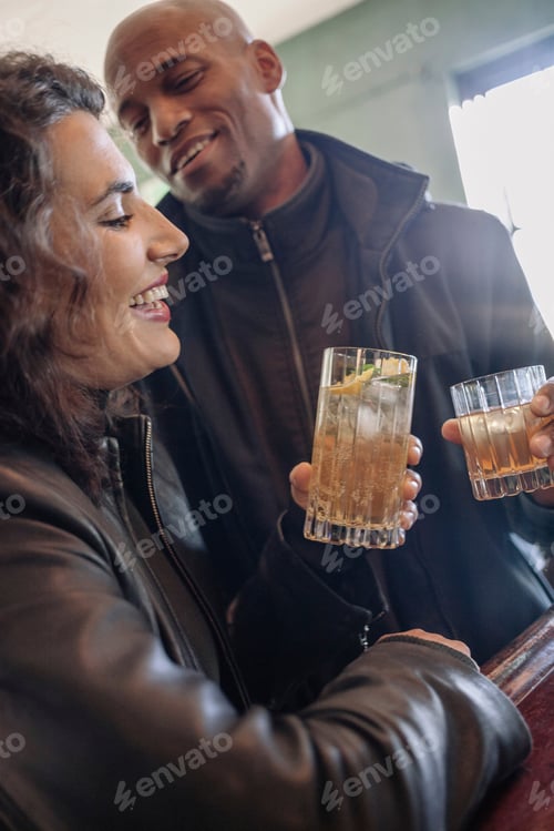 Preview: Two friends sharing a toast with cocktails at a cozy bar
