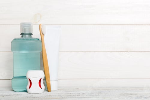 Preview: Mouthwash and other oral hygiene products on colored table top view with copy space