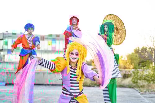 Preview: Group of harlequins in colorful costumes holding crystal balls.