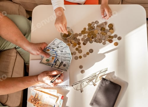 Preview: Senior woman and little child hands counting paper money American dollars. Euro and coins at home