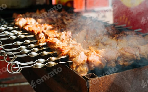 Preview: Grilled meat on skewers outdoors. Smoke and aroma rising from the barbecue.