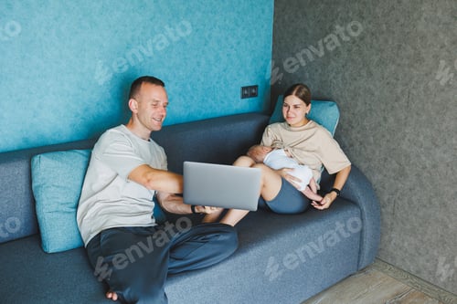 Preview: Happy family mom, dad and cute baby son having fun using laptop at home. Young parents and funny