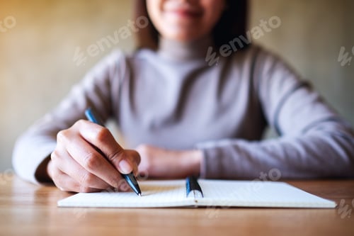 Preview: Closeup image of a woman writing on a blank notebook on the table