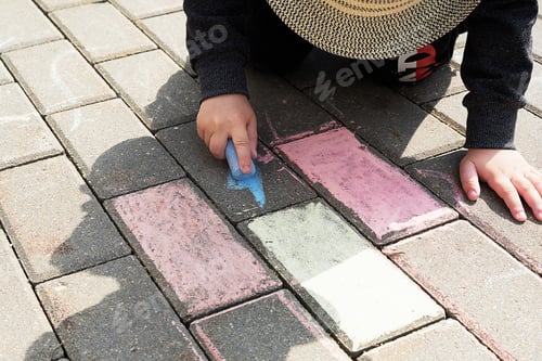 Preview: child drawing with chalk on asphalt. boy playing alone in the street.