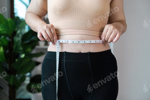 Preview: Person Measuring Waist with Tape Measure in Fitness Clothing to Track Weight Loss or Health Progress
