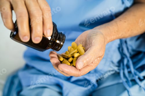 Preview: Asian doctor holding and pour and hold vitamin c pills medicine from the bottle to patient