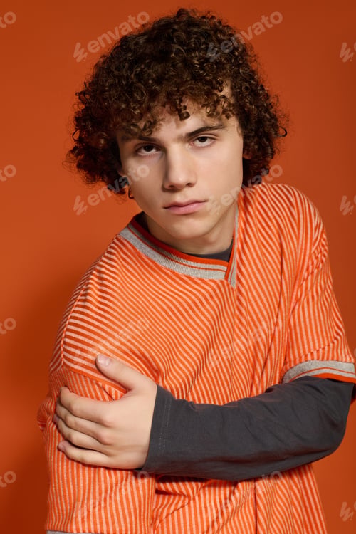 Preview: Teenage boy showcases unique style against vibrant orange backdrop