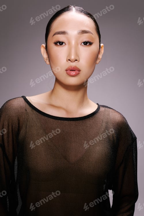 Preview: Asian woman in sheer top posing with hands on hips for camera fashionable and stylish look