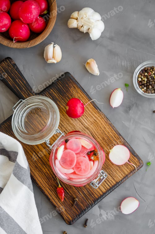 Preview: Fermented food. Marinated radish with onion, garlic and spices in a jar on a cutting board
