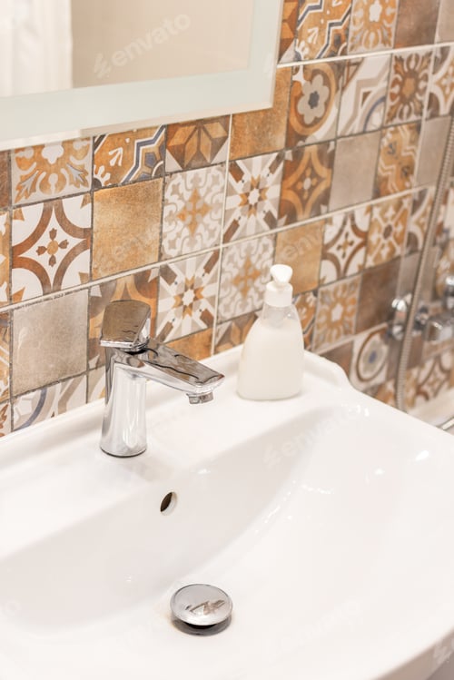 Preview: Bathroom interior. Sink, beige ceramic tile, metal faucet, white soap, close-up mirror.