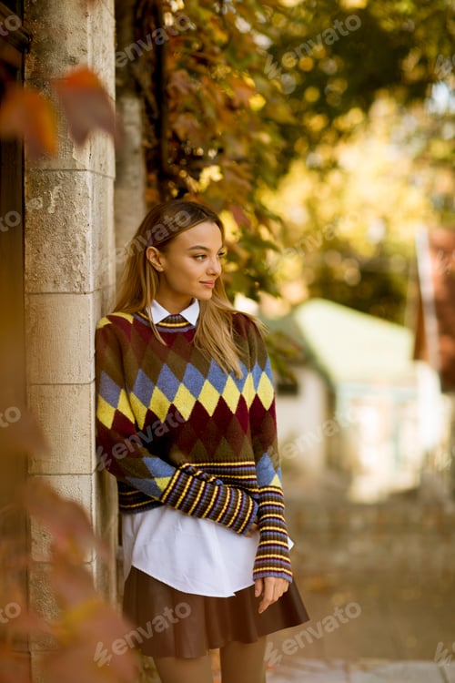 Preview: Young woman standing outside at sunny autumn day