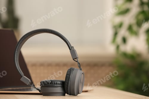 Preview: Modern headphones and laptop on table indoors, space for text