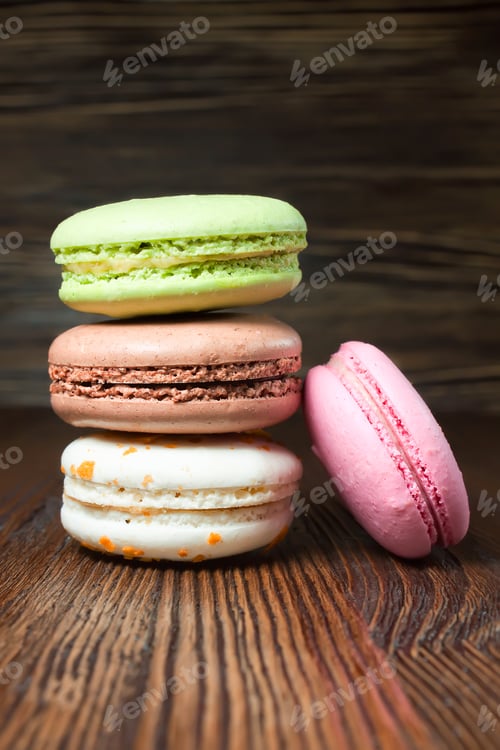 Preview: A stack of colorful traditional French dessert makarons on brown wooden background.