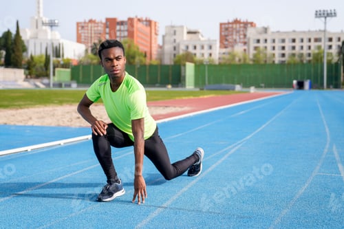 Preview: A african man in a green shirt is stretching on a track