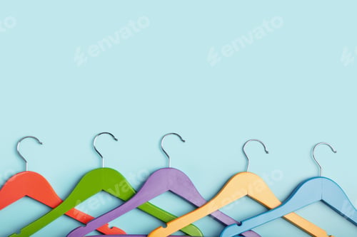 Preview: Five children's hangers for clothes of rainbow colors. Blue background.