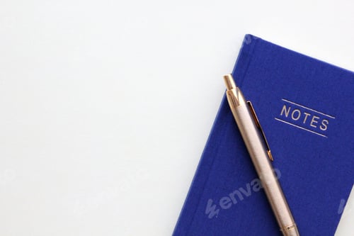 Preview: Flat lay blue notebook and gold pen on a white background