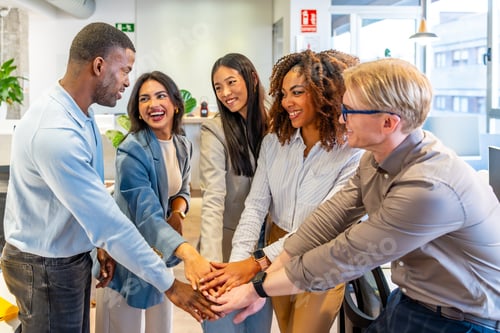 Preview: Happy multiethnic business team joining hands in coworking office