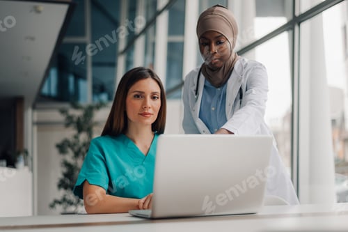 Preview: Two female doctors using laptop are working in hospital office